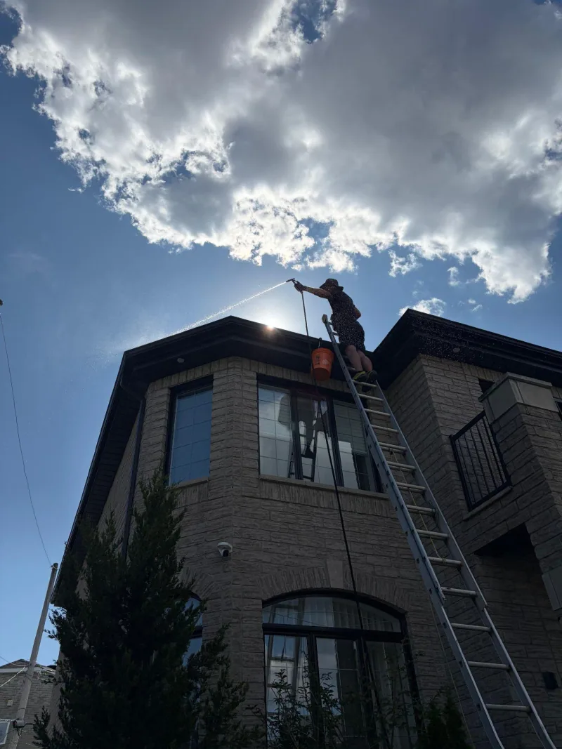 An EDMTL team member working from a ladder at the roofline of a home.