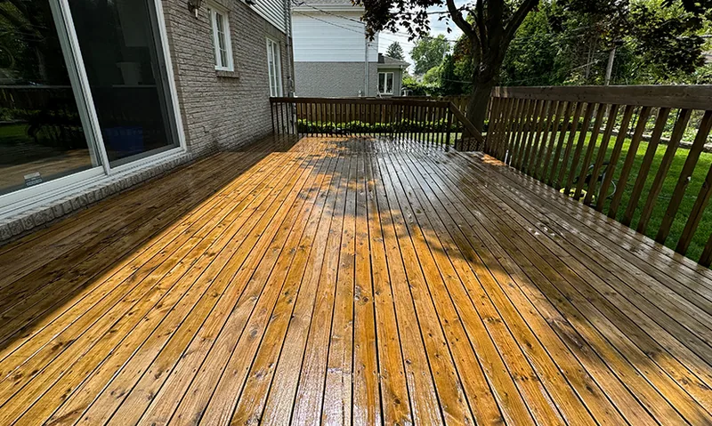 A wood deck beside a house with a garden beyond the railing.
